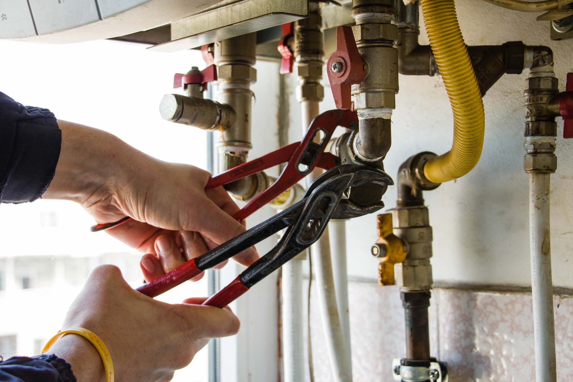 A worker attaches the pipe to the gas boiler.